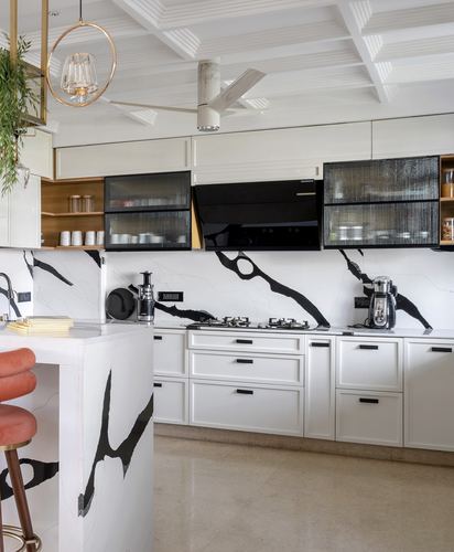 White kitchen with black-veined stone backsplash and island, black glass cabinets, coffered ceiling