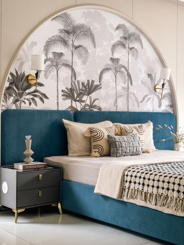 Teal velvet bed against arched palm-print mural with brass sconces and grey nightstand