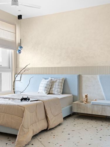 Minimalist bedroom with blue upholstered headboard, plaster wall, and terrazzo floor