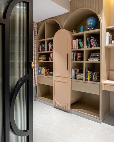 Arched wooden bookshelves with a peach curved door beside a black reeded glass entry door