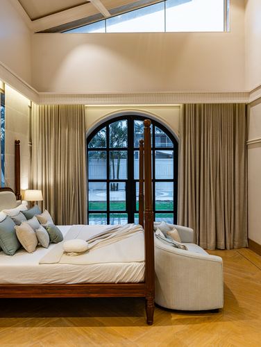 Bedroom with carved four-poster bed facing arched glass door and garden view