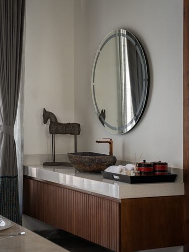 Bathroom vanity with stone vessel sink, oval mirror, and fluted wood cabinetry