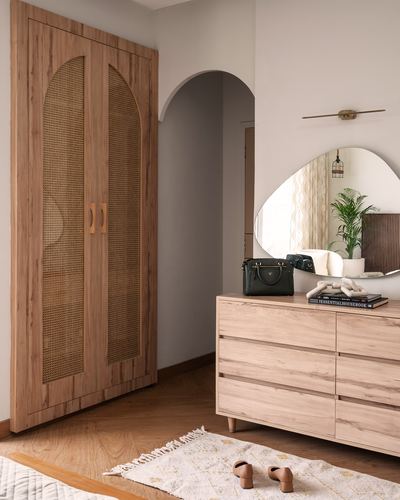 Wooden wardrobe with cane arched doors beside an archway and dresser with asymmetric mirror