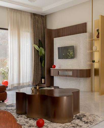 Living room with sculptural wavy coffee table, marble tv wall panel and brass shelving