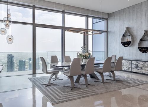 High-rise dining room with sculptural chairs, marble table, and panoramic Dubai skyline view