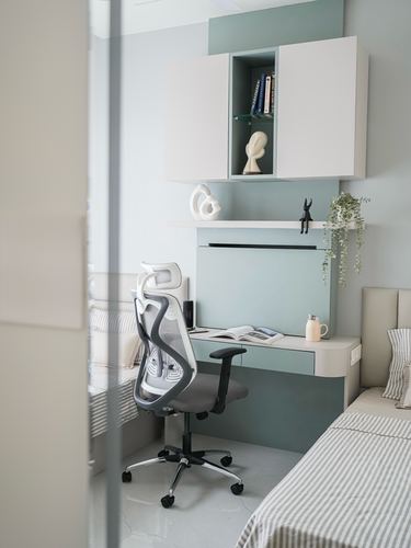 Wall-mounted study nook with mesh office chair between two striped beds, seen through a doorway