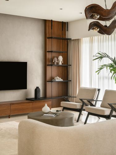 Living room with wood-slat shelving, TV console, cane accent chairs and sculptural pendant lights