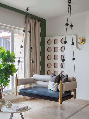 Suspended swing sofa with navy leather seat in front of a circular cutout wall panel and green scalloped niche