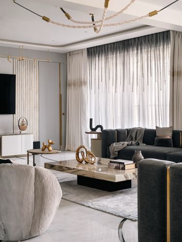 Living room with dark sofa, marble coffee table, beaded curtains and gold decorative accents