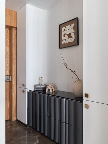 White foyer corridor with fluted black console, brass hardware, and framed textile art