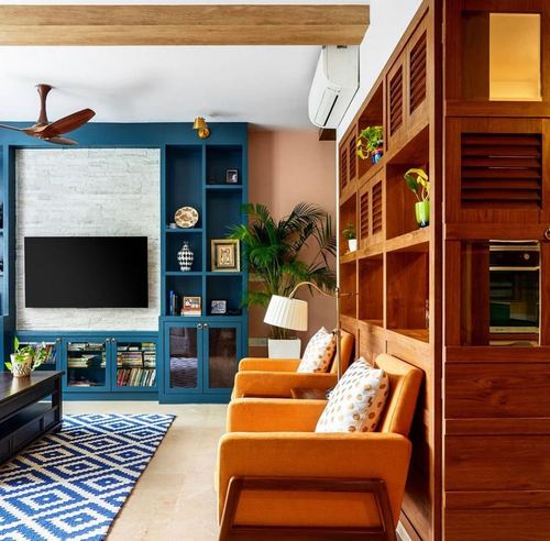Living room with blue built-in TV unit, orange armchairs, and wooden slatted partition