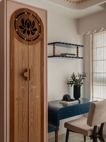 Carved wooden wardrobe with lotus motif beside a navy study desk and chair