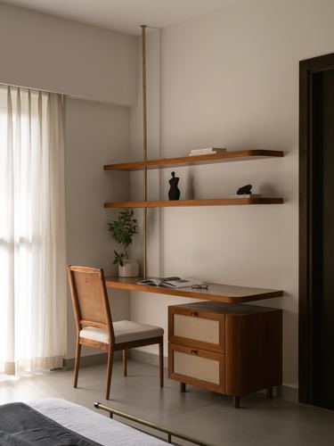 Wood desk and floating shelves against beige wall, cane chair and cane-front drawer unit below.