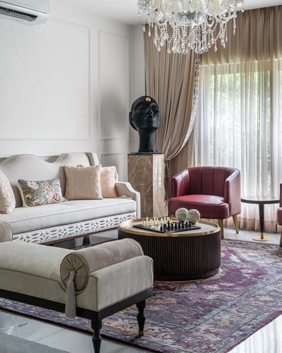 Elegant living room with beige sofa, maroon armchair, round coffee table, chandelier and sculptural bust