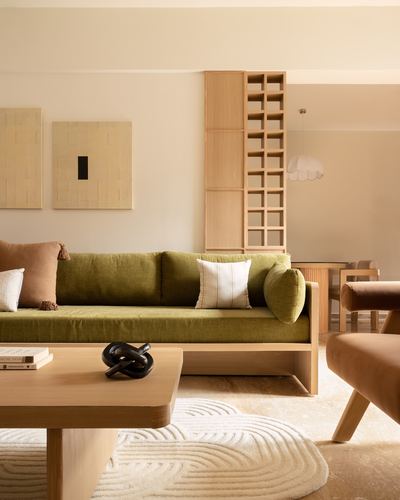 Olive green low sofa against wood lattice shelving in a warm-toned Japandi living room