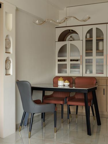 Dining nook with marble-top table, terracotta and grey chairs, and arched glass cabinetry behind