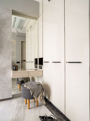 Foyer dressing nook with mirrored wardrobe, woven pouf, and marble floor