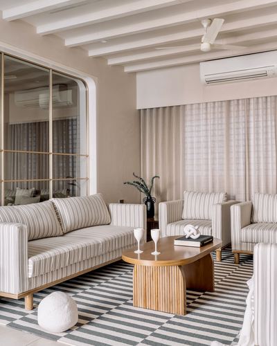 Neutral striped living room with fluted wood coffee table and checkered rug, exposed beam ceiling