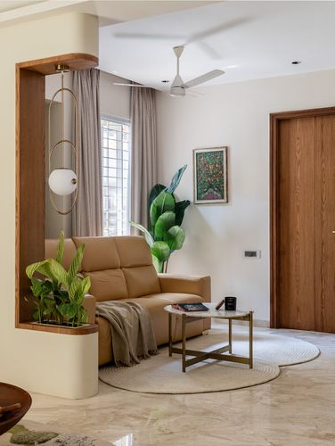 Living room corner with tan leather sofa, marble floor, round rug and wooden door