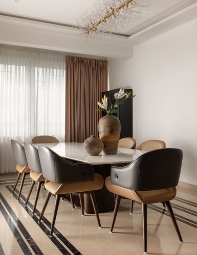 Dining room with marble-top table, black and tan leather chairs, and sculptural vases against sheer curtains