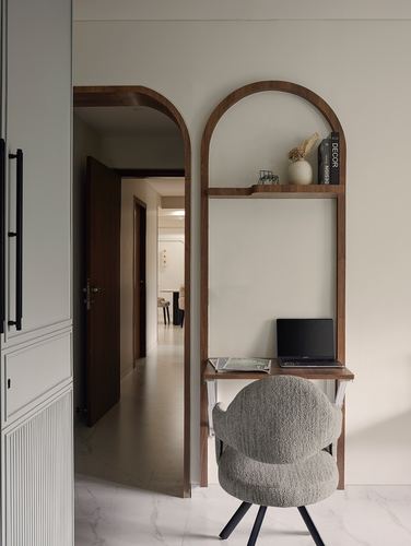 Arched wood desk-shelf unit with boucle chair beside an arched hallway doorway