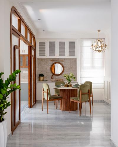 Dining nook with round fluted wood table, green velvet chairs, and arched wooden doorway