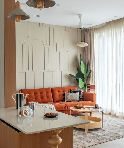 Living room with orange velvet sofa against textured cream relief wall and pendant lights