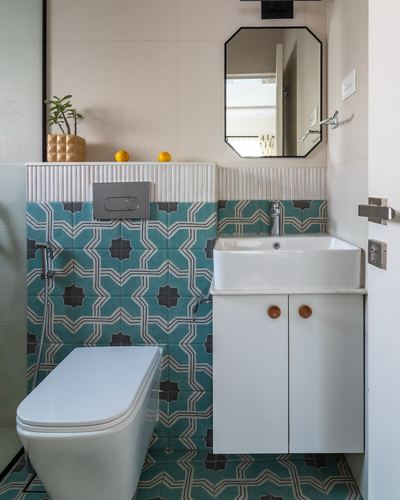 Bathroom with teal star-patterned tiles, wall-hung white sink, and octagonal mirror
