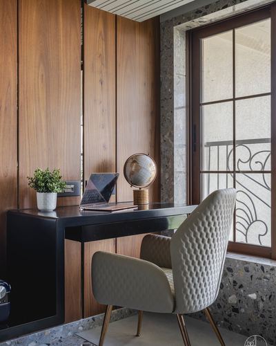 Study nook with black desk, quilted chair, globe, wood panelling and terrazzo window frame