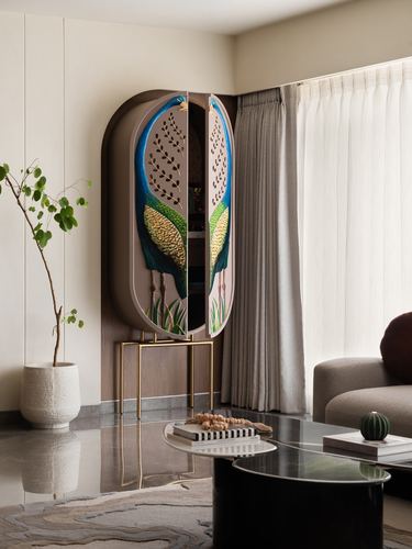 Oval peacock-painted cabinet on brass legs in a neutral-toned Mumbai living room