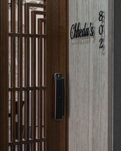 Close-up of a dark wood entrance door with lattice grille beside a stone wall nameplate reading Chheda's 802
