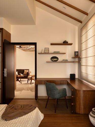 Wooden study nook with floating shelves and desk beside open door to living room