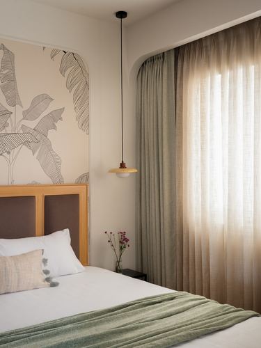 Bedroom corner with leaf-print wallpaper niche, pendant light and sheer curtained window