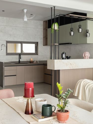 Kitchen with sage cabinetry and pendant lights seen past a styled dining table with candle and plants