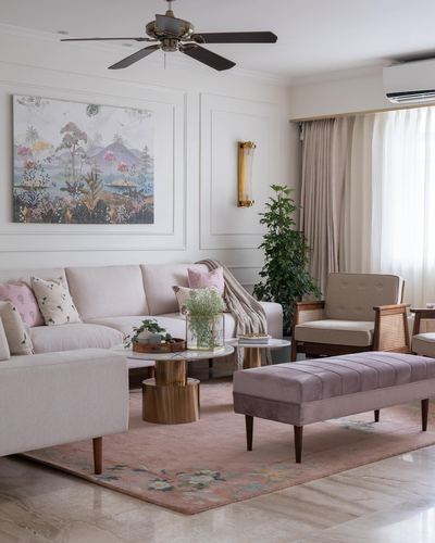 Pastel living room with cane armchair, blush bench, marble floor and framed landscape painting