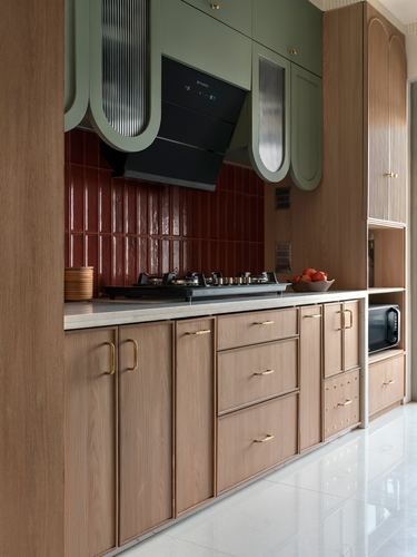 Kitchen with arched sage cabinets, wood base units, and a ridged red tile backsplash behind the stove