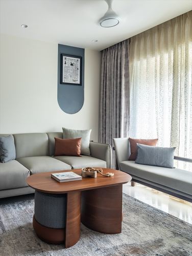 Minimalist living room with grey sofas, curved wood coffee table, sheer curtains, framed newspaper art