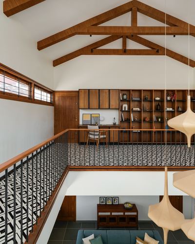 Mezzanine study with wooden truss ceiling, patterned tile floor, and shelving overlooking a double-height living room