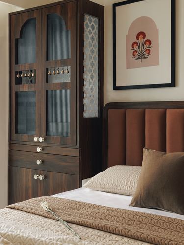 Dark wood arched-door wardrobe beside a terracotta channel-tufted headboard with layered beige bedding