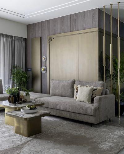 Living room with taupe sofa, brass wall panel, and marble-top brass coffee tables