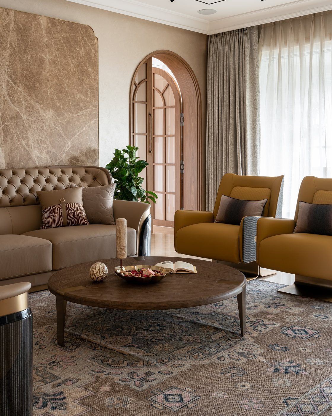 Living room with mustard armchairs, tufted sofa, round wood coffee table and arched glazed door