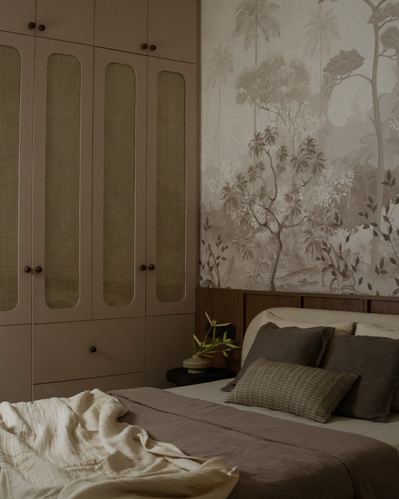 Bedroom with cane-front wardrobe beside bed under a forest mural wallpaper