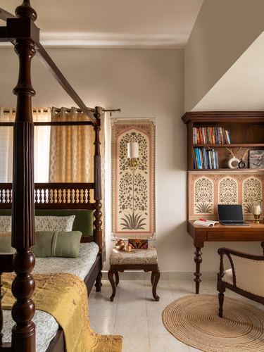 Traditional bedroom with carved four-poster bed, floral wall panel, and wooden study desk in Dharwad home