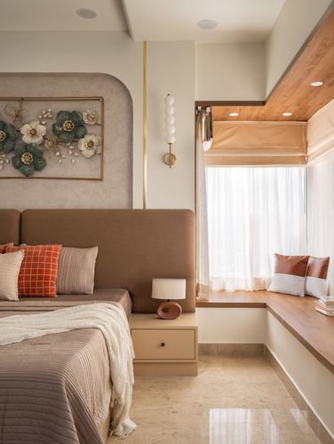 Neutral-toned bedroom with upholstered headboard, floral wall art, and wood-topped window seat