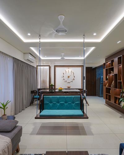 Teal velvet swing hangs over dining table in a warm-toned contemporary living room