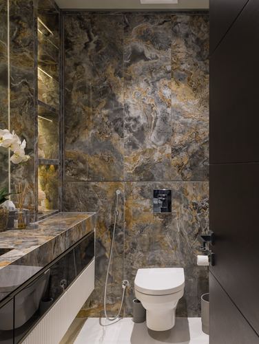 Bathroom with dramatic veined stone walls, wall-hung toilet and floating marble vanity