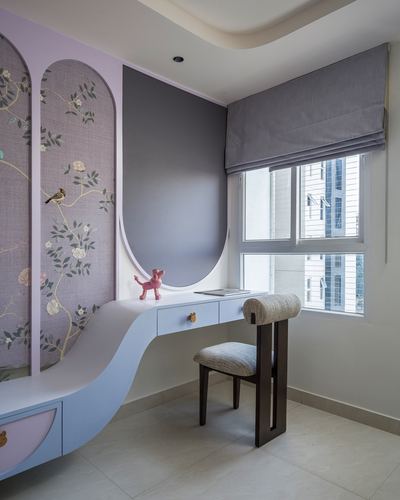 Curved lavender study nook with arched wallpaper panel, desk, and window seat under a fluted ceiling.