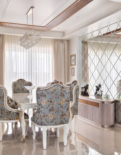 Formal dining room with floral chairs, crystal chandelier, and mirrored diamond-pattern wall