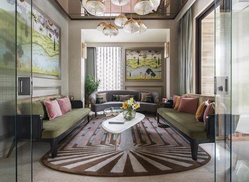 Symmetrical living room with curved olive sofas, sunburst rug, and cluster pendant chandelier in Jaipur home