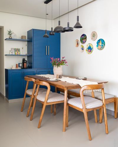 Dining area with navy blue cabinetry, wooden table and chairs, and decorative plates on the wall